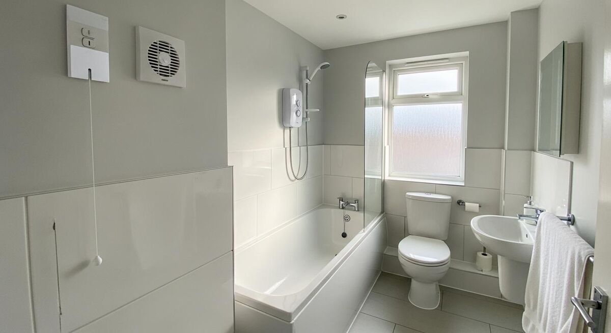 UK bathroom showing compliant electrical fittings including IP-rated light fitting and pull cord switch