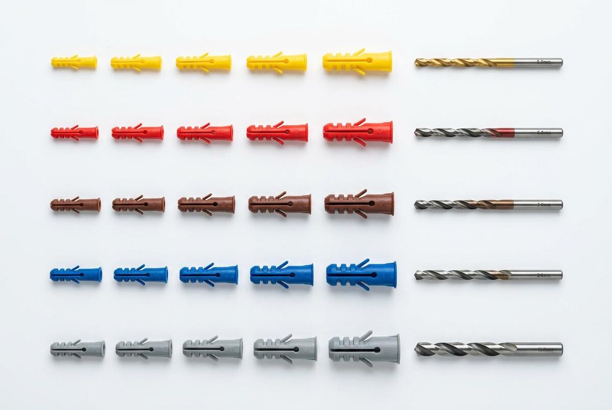 Wall plugs arranged by colour from yellow to grey with corresponding drill bits