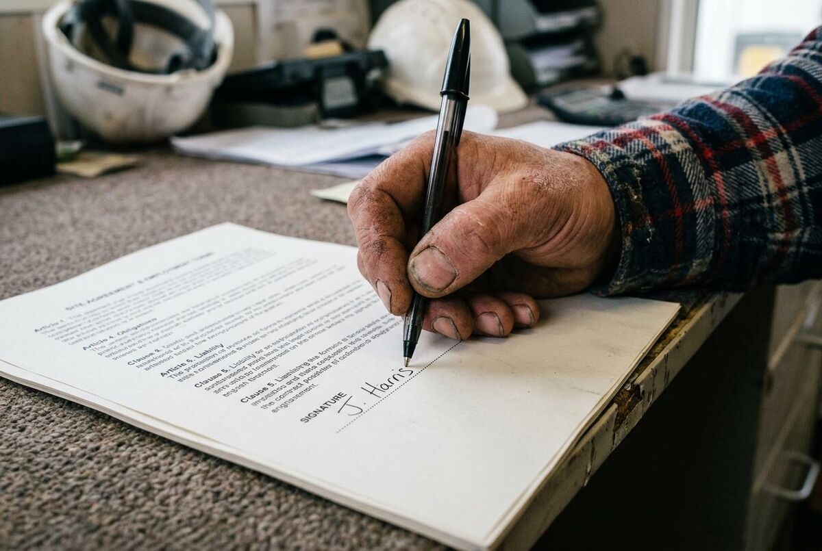 A tradesperson signing a subcontractor agreement before work begins