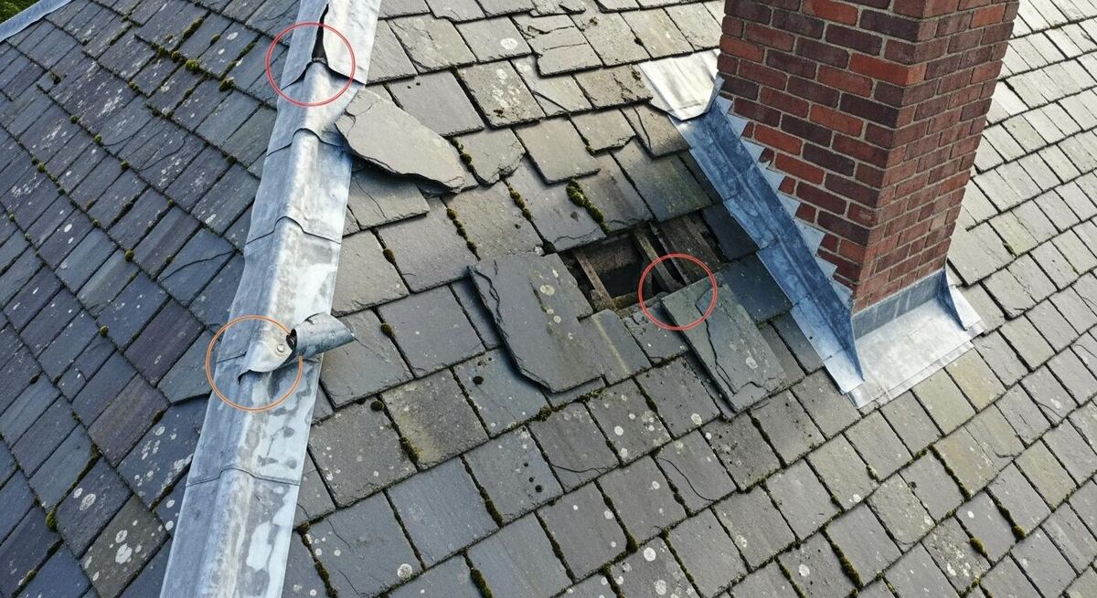 A drone image of a slate roof with coloured outlines marking cracked tiles, lifted flashing, and a missing piece of lead work