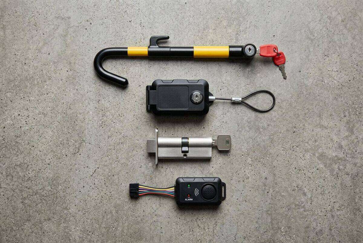 Overhead flat-lay showing layered van security products including steering lock, deadlock cylinder, GPS device, and alarm module